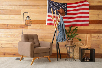 Interior of modern hallway with brown armchair, clothes rack and USA flag on wooden wall