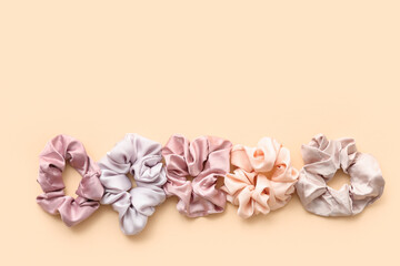 Trendy silk scrunchies on light yellow background