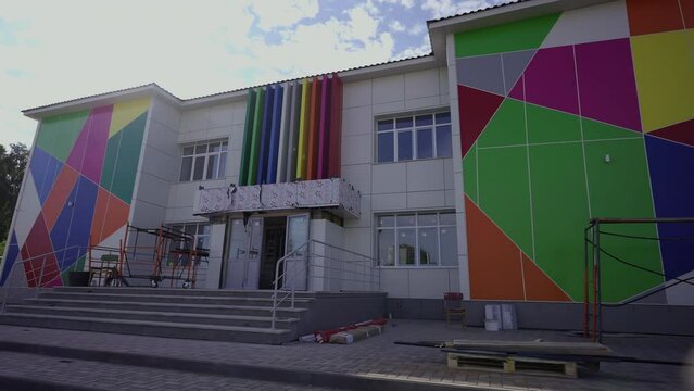 Unfinished kindergarten exterior with protective foil and color ornament in city district. Fancy facade of preschool building at construction site