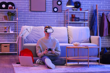 Male student in VR glasses playing video game at home in evening