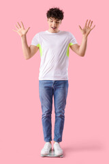Handsome young happy sporty man with scales on pink background. Weight loss concept
