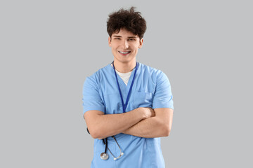 Male medical intern with stethoscope on light background