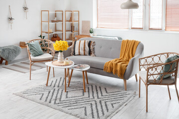 Grey sofa, armchairs, coffee table and vase of narcissus flowers in beautiful living room