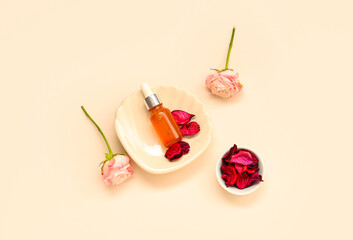 Beautiful composition with bottle of cosmetic product, saucer, roses and petals on beige background