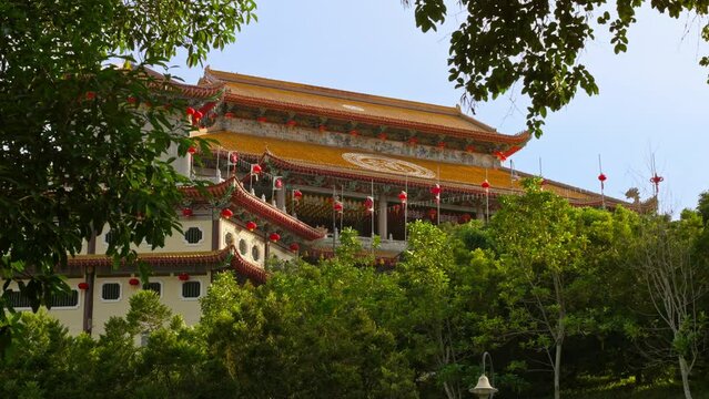 View of the Kek Lok Si Temple from a distance through some green tree foliage with parallax camera movement, George Town, Penang, Malaysia