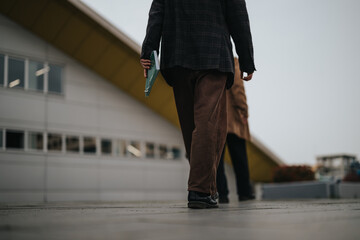 Low angle view of a businessperson strolling with files outside a contemporary structure, exuding...