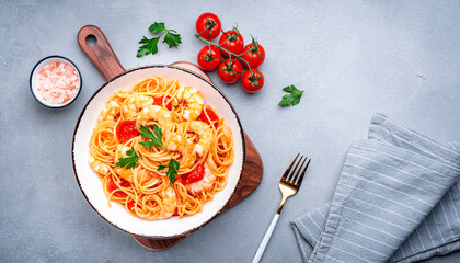 Cooked Italian spaghetti pasta with shrimp and tomato sauce, gray table background, top view
