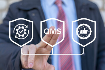 Business man working on virtual touch screen presses abbreviation: QMS. Quality Management System ( QMS ) concept. Formalized system for achieving quality policies and objectives.