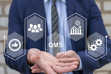 Businessman using virtual touch screen presses text: QMS. QMS - Quality Management System concept. Standards, Documentation, Processes, Audits, Improvement, Compliance, Training, Customer, Continual.