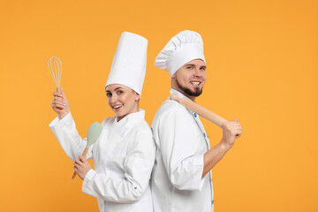 Happy confectioners in uniforms holding professional tools on yellow background