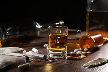 Alcohol and drug addiction. Whiskey in glass, syringes, pills and cocaine on wooden table