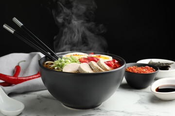 Delicious hot ramen in bowl on white marble table against black background, closeup. Noodle soup