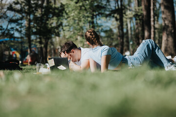 A young couple is seen lying on the grass, immersed in their study materials on a bright, sunny day...