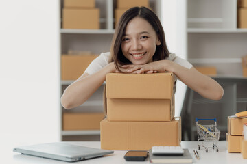 Starting business, Asian woman working as SME entrepreneur, new business with laptop packaging box,...