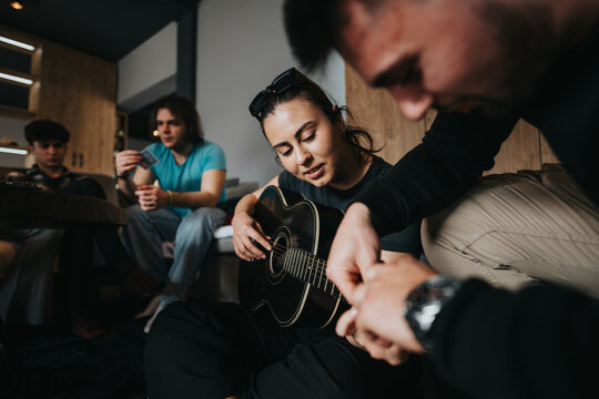 A close-knit group of friends gather together for an intimate guitar session in a cozy indoor setting, sharing moments of joy. - Powered by Adobe