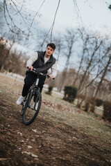 Young male teenager rides a bike on a dirt path in a park, conveying a sense of freedom and youthful leisure.