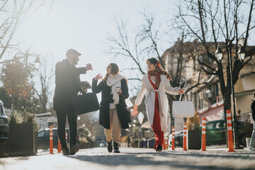 A group of fashionably dressed friends enjoying a conversation while walking along a sunny, urban street lined with trees.