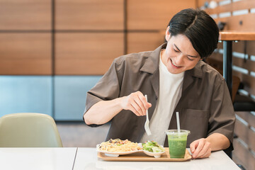 カフェでランチ・パスタを食べる若いアジア人男性
