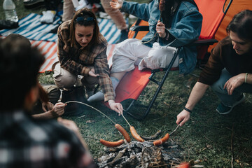 Group of friends gathered around a campfire, roasting sausages and enjoying a laid-back outdoor...