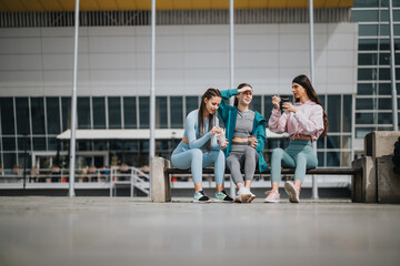 A group of three friends relaxing and chatting after some fitness activity, wearing sporty outfits...