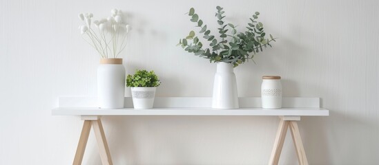 Three decorative vases of different sizes placed on a wooden table alongside green potted plants - obrazy, fototapety, plakaty
