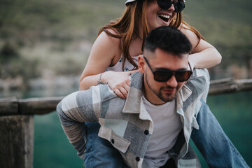 A playful couple shares joyful laughter during an outdoor trip, highlighting their vacation on a...