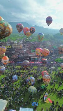 Drone view of Hot Air Balloon Festival in Wonosobo, Indonesia. Colorfull hot air balloon festival is similar in Cappadocia. Vertical orientation for reels or shorts video.