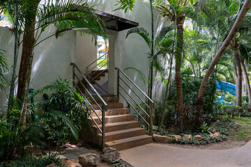 Stone staircase with metal railings leading up to the swimming pool in the courtyard of a condominium at a tropical resort.
