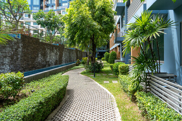 A stone paver path winds through bushes and tropical trees in the courtyard of a condominium at a tropical resort.