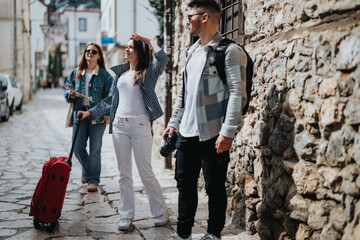 Group of young tourists with luggage sightseeing and enjoying their trip in a picturesque town on a...