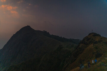 Naklejka premium A mountain range with a cloudy sky and a person standing on top of it