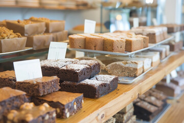 Bright and airy bakery shelf stocked with gluten-free confections, such as date brownies and chickpea blondies, inviting atmosphere 