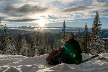 man watches a snowy sunset in the forest
