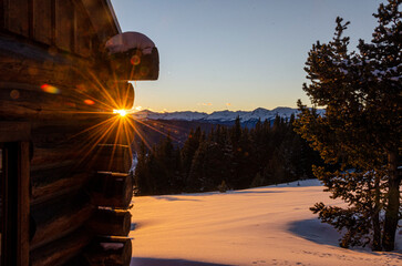 sunrise through the cracks in a log cabin wall