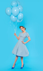 Pin-up girl in dress and heels with balloon on blue background