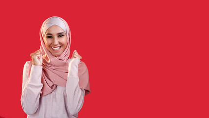Winner yes. Victory joy. Positive reaction. Pleased satisfied excited cheerful happy woman in headscarf isolated on red empty space background. - 792295518