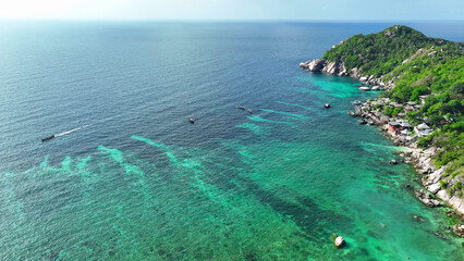 Lush trees frame a pristine sandy shore, where azure waters embrace a stunning resort. Nature's beauty in perfect harmony. Top view Aerial view of drone. Gulf of Thailand. Beach background. 
