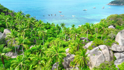 Emerald woodlands meet distinctive formations along the coast, where azure waters glisten in...