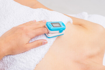 Woman using pulse oximeter at home. Female hand and medical equipment. Healthcare concept.