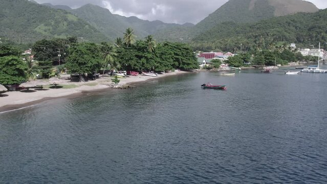 Aerial drone video of Soufriere beach with boats in the harbor in front of Petit Piton on Saint Lucia island.