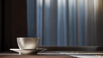 a morning hot coffee in white cup in sunshine scene with shade and white smoke from hot water