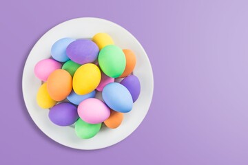 Colorful fresh Easter eggs in plate on colored background