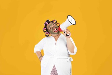 Portrait of a fat housewife wearing a natural mask and holding a megaphone isolated on a yellow color background