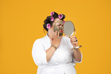 Close-up portrait of fat and angry housewife wearing natural mask looking in the mirror isolated on...