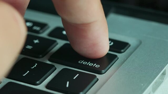 Finger of the computer user, he presses the delete button on the computer keyboard	
