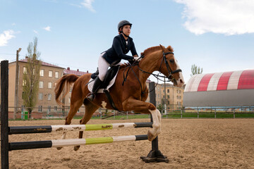 Rider jumping horse over obstacle, equestrian sport.