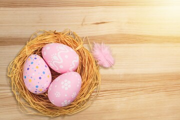 Colorful fresh Easter eggs in basket on wood background