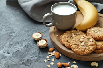 Healthy homemade oatmeal cookies with banana oats nuts on a wooden tray and a cup of milk Suitable for text - Powered by Adobe