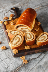 Nut roll is a pastry consisting of a sweet yeast dough with a nut paste made from ground nuts and honey closeup on the wooden board on the table. Vertical