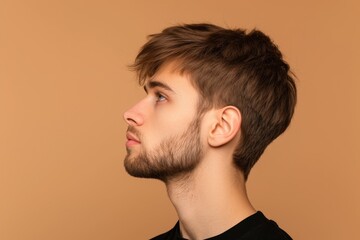 Profile photo of confident young handsome man with stubble on beige background